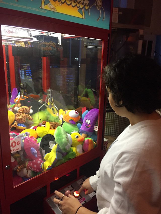 Local youth Sam Corbin tries her hand at the claw machine. It's unclear if the arcade games will survive into the new iteration. 